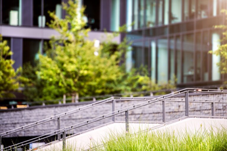 Stairs in front of glass buildings. Business office. Park with trees and grass in front of the Business center.